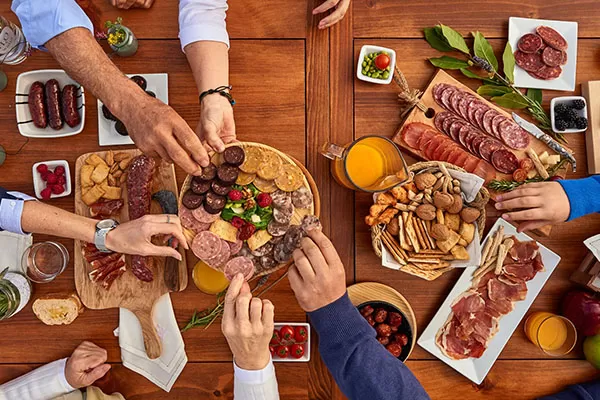 se ve una familia desde arriba compartiendo unas tablas de embutidos ibericos